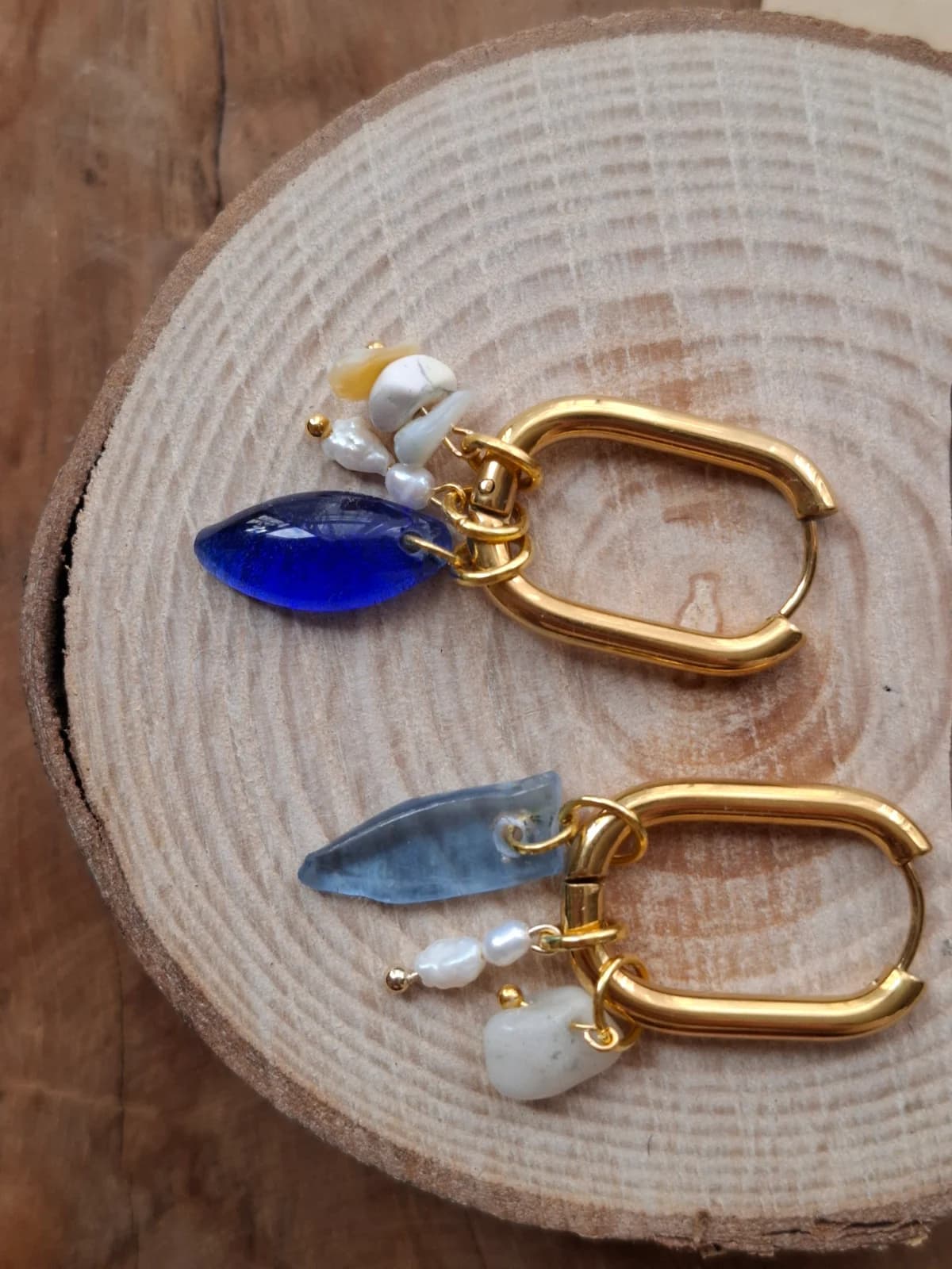 Boucles d'oreilles dorées rectangulaires suspendues avec pampilles blanches et verre recyclé bleu.