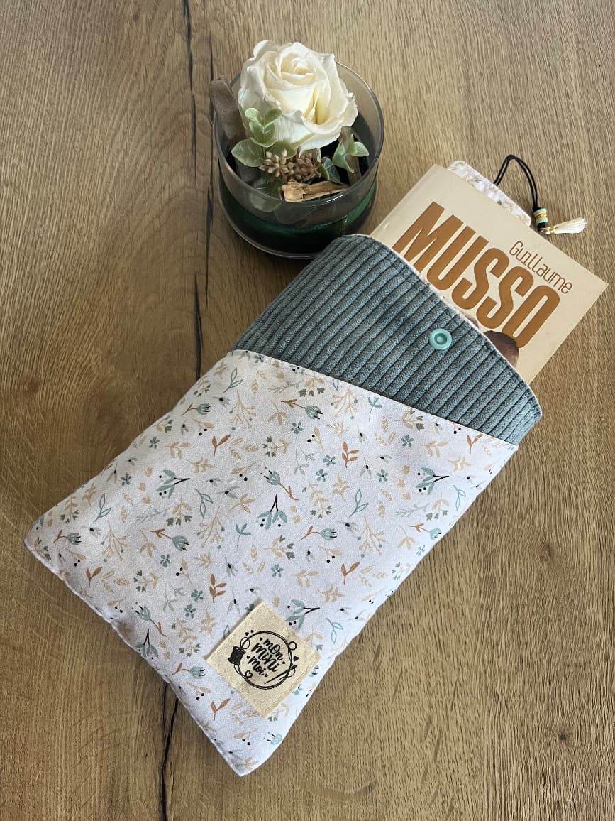 Livre de poche inséré dans la pochette de lecture en velours côtelé bleu jean et tissu à motifs floraux.