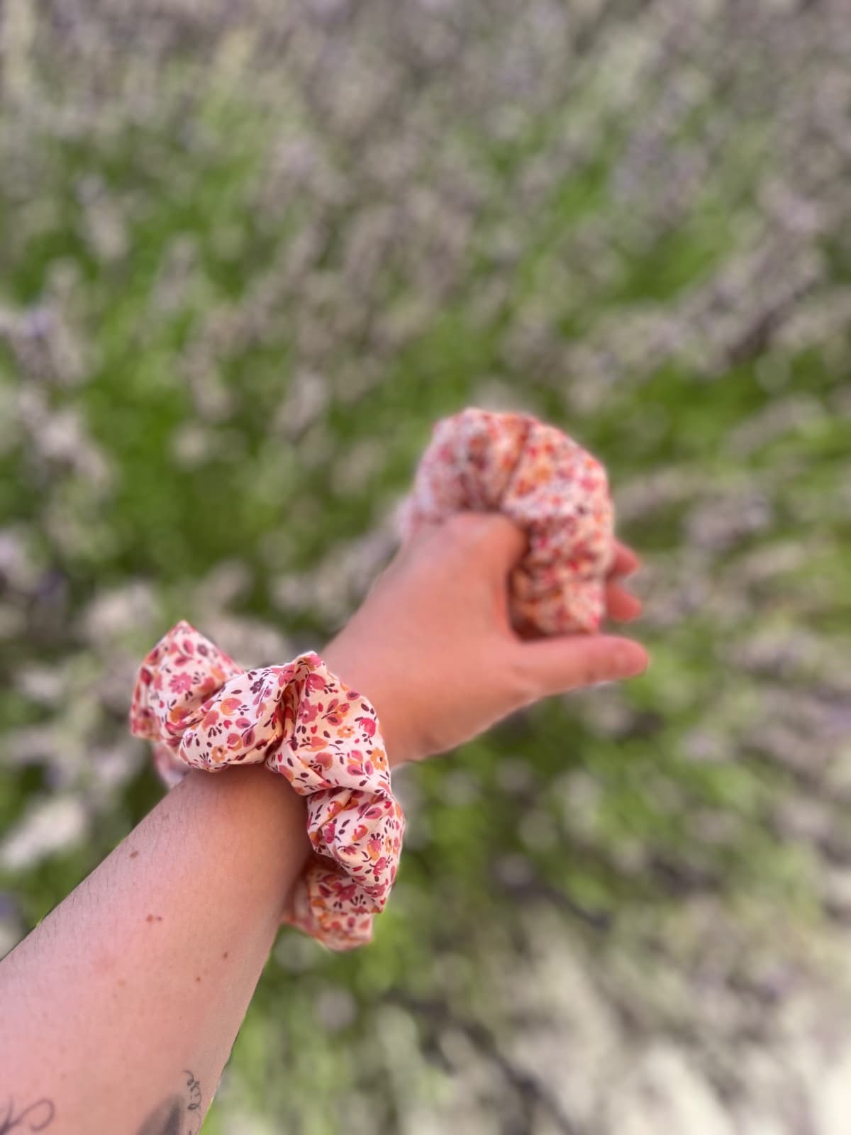 Chouchou fleuri rose et bordeaux porté au poignet, en extérieur.