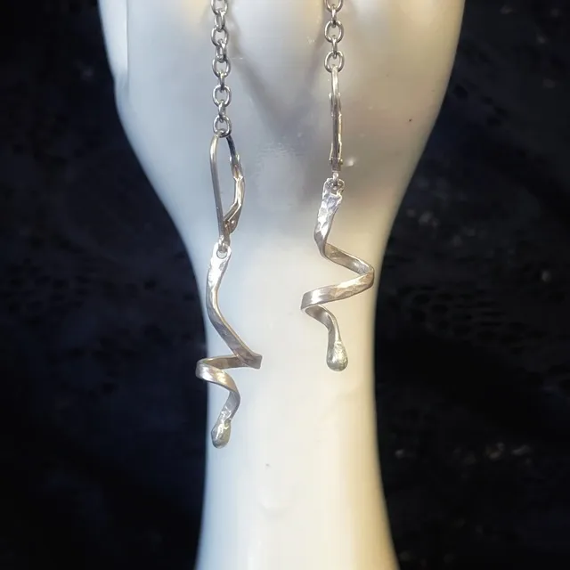 Paire de boucles d'oreilles pendantes spirales en argent 925 sur présentoir main blanc