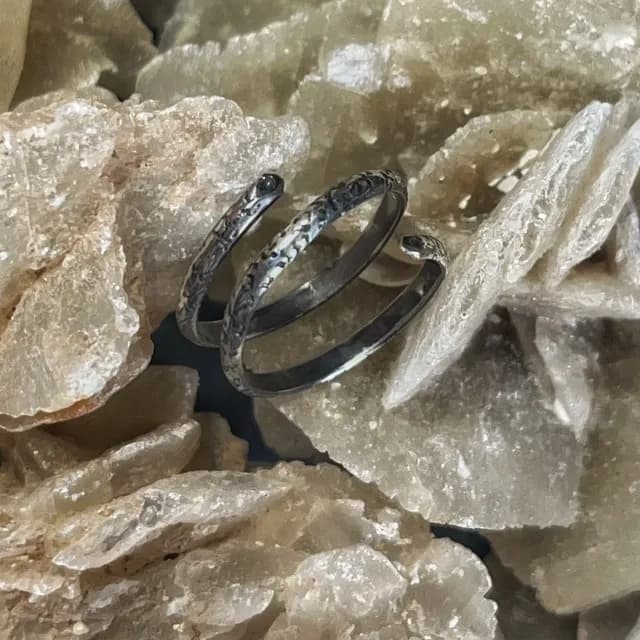 Bague de phalange réglable en spirale gravée en argent 925, posée sur une roche minérale.
