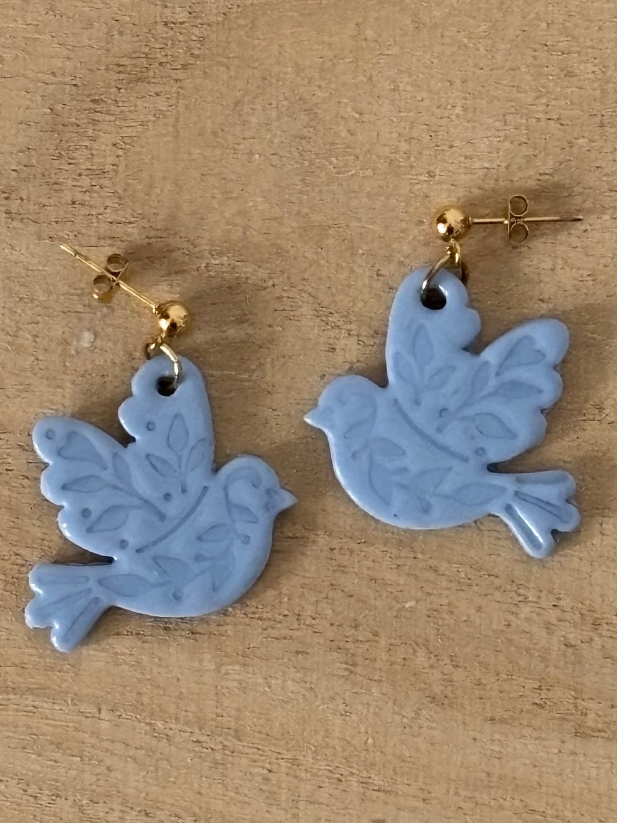 Boucles d'oreilles pendantes en forme d'oiseaux bleu gris gravés de motifs végétaux sur support bois